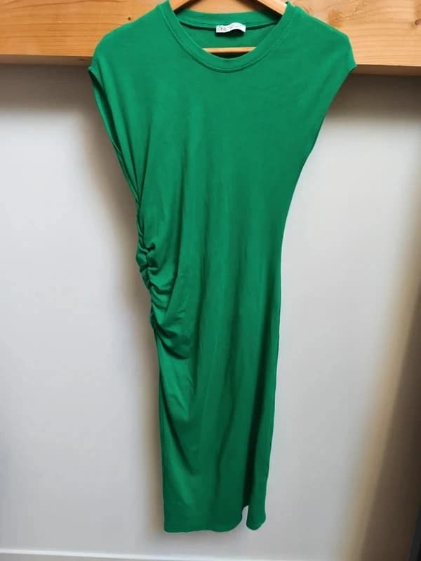 Photo brute d'une robe verte moulante et longue posée sur le lit — avant IA