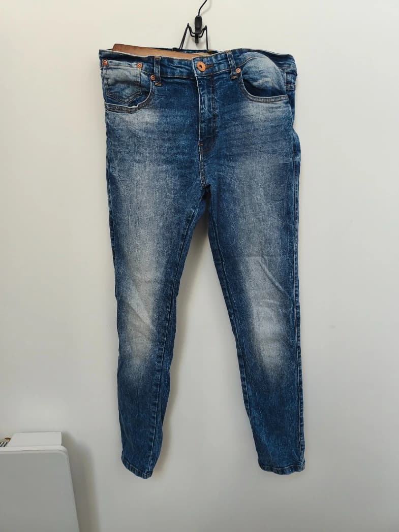 Photo d'un jean slim accroché au mur sur un cintre — avant IA